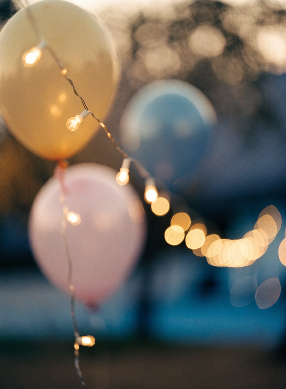 Warm string fairy lights and pastel balloons at a birthday party
