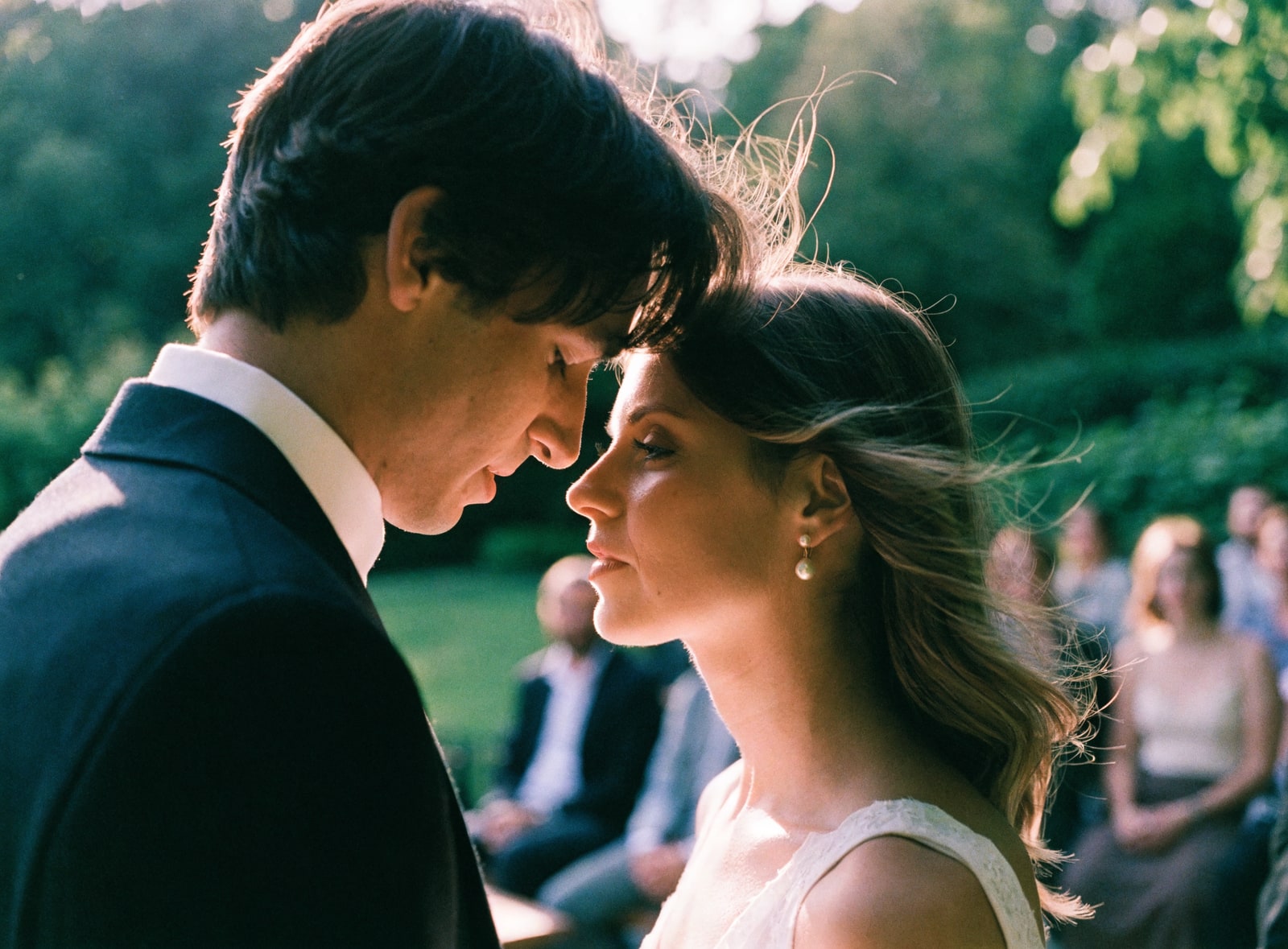 A couple exchanging vows at an outdoor garden wedding ceremony in golden light